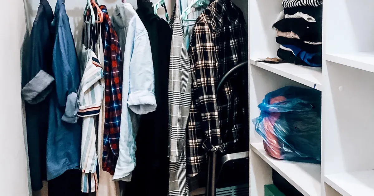 A dresser drawer with shirts standing upright in neat rows using the file-fold method, all visible at a glance. Warm natural light, tidy bedroom setting.