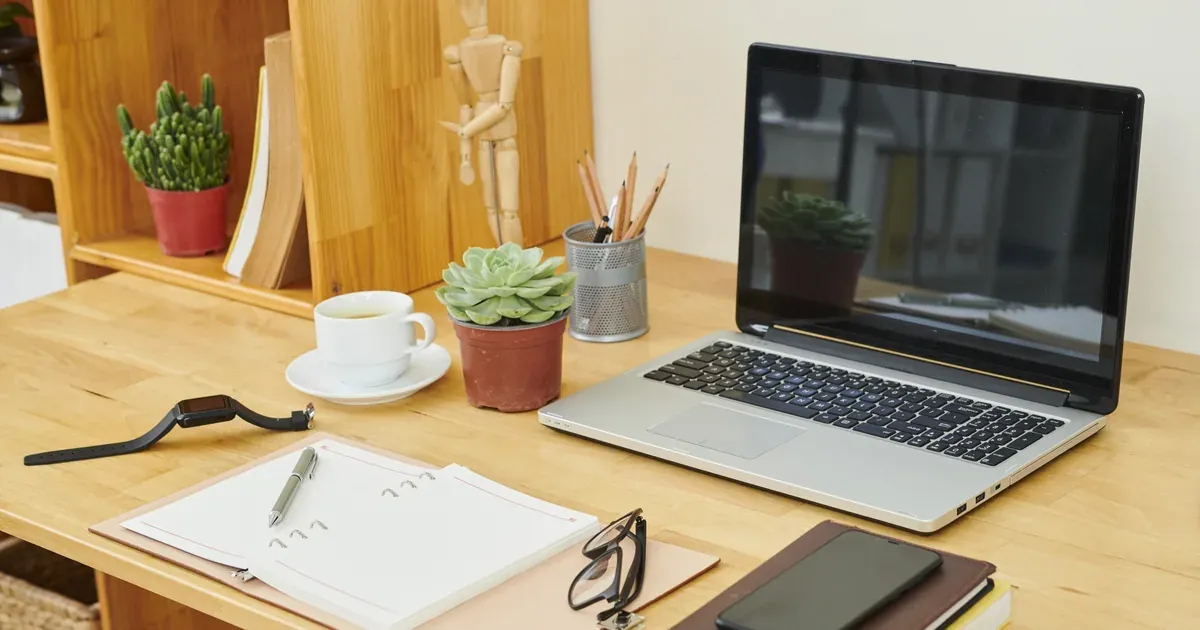 A clean, well-organized home office desk with a bamboo desktop organizer, monitor riser, and routed cables — natural light, minimal clutter on surface.