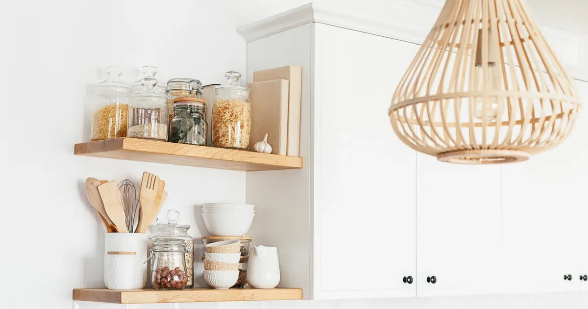 A kitchen pantry cabinet open to reveal labeled clear bins and a pull-out shelf, mid-organization.