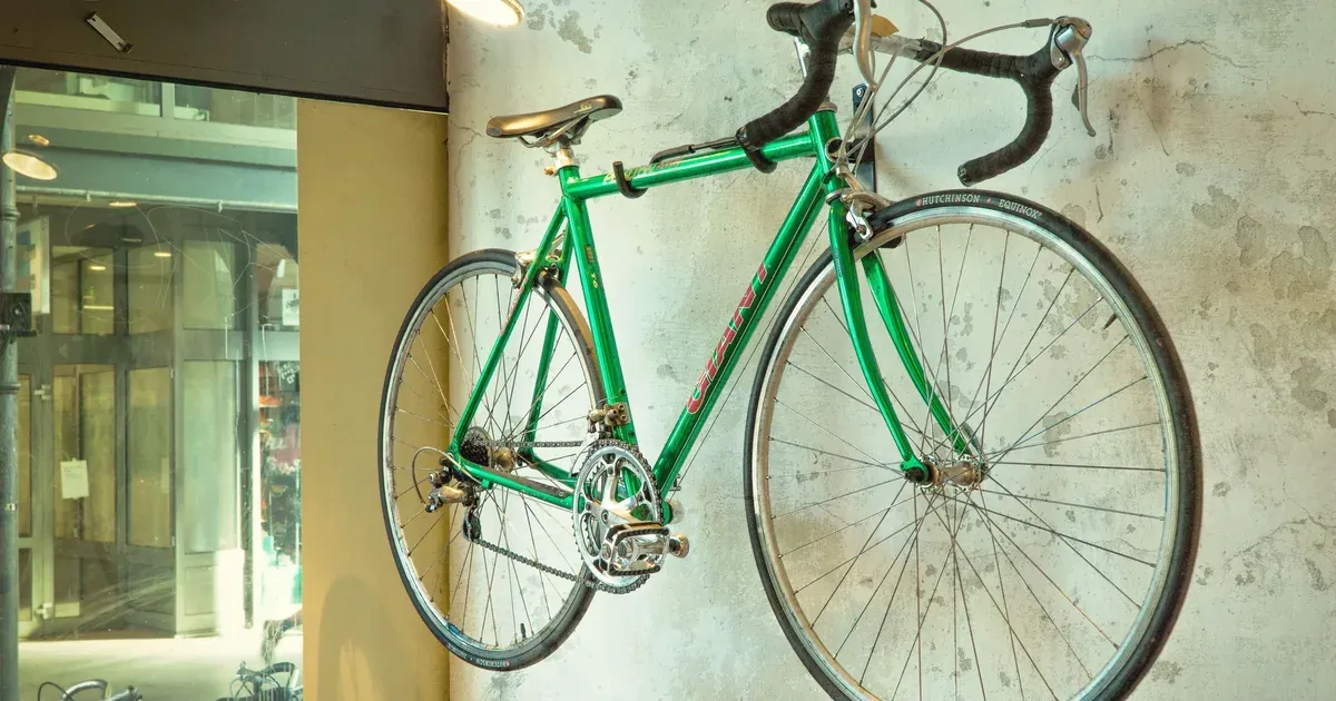 A garage wall with several bikes hung vertically on hooks above a clear, organized floor.