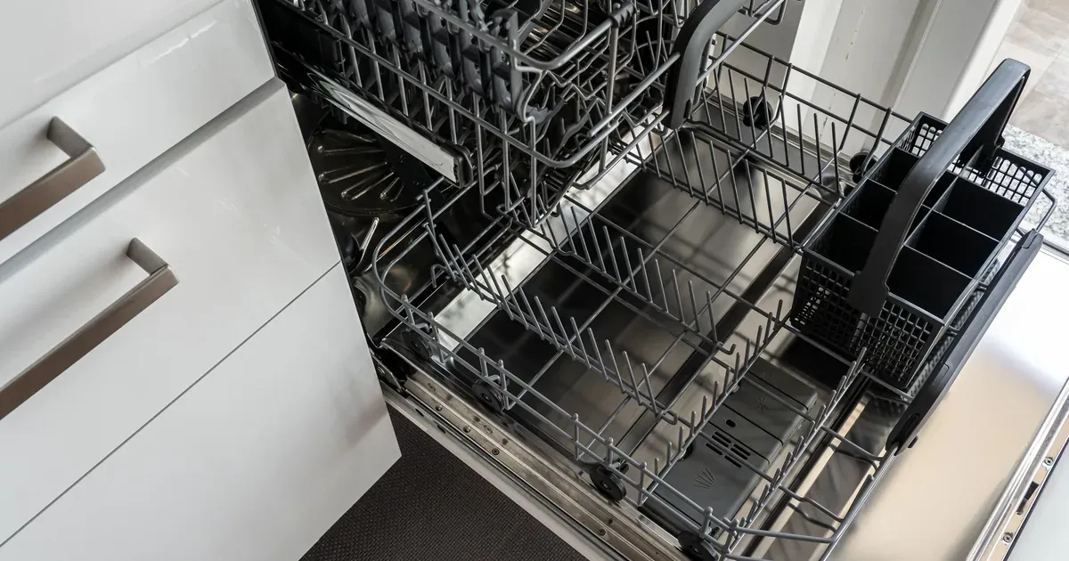 Open dishwasher with bottom rack pulled out, hands cleaning the filter, sparkling clean dishes in background.