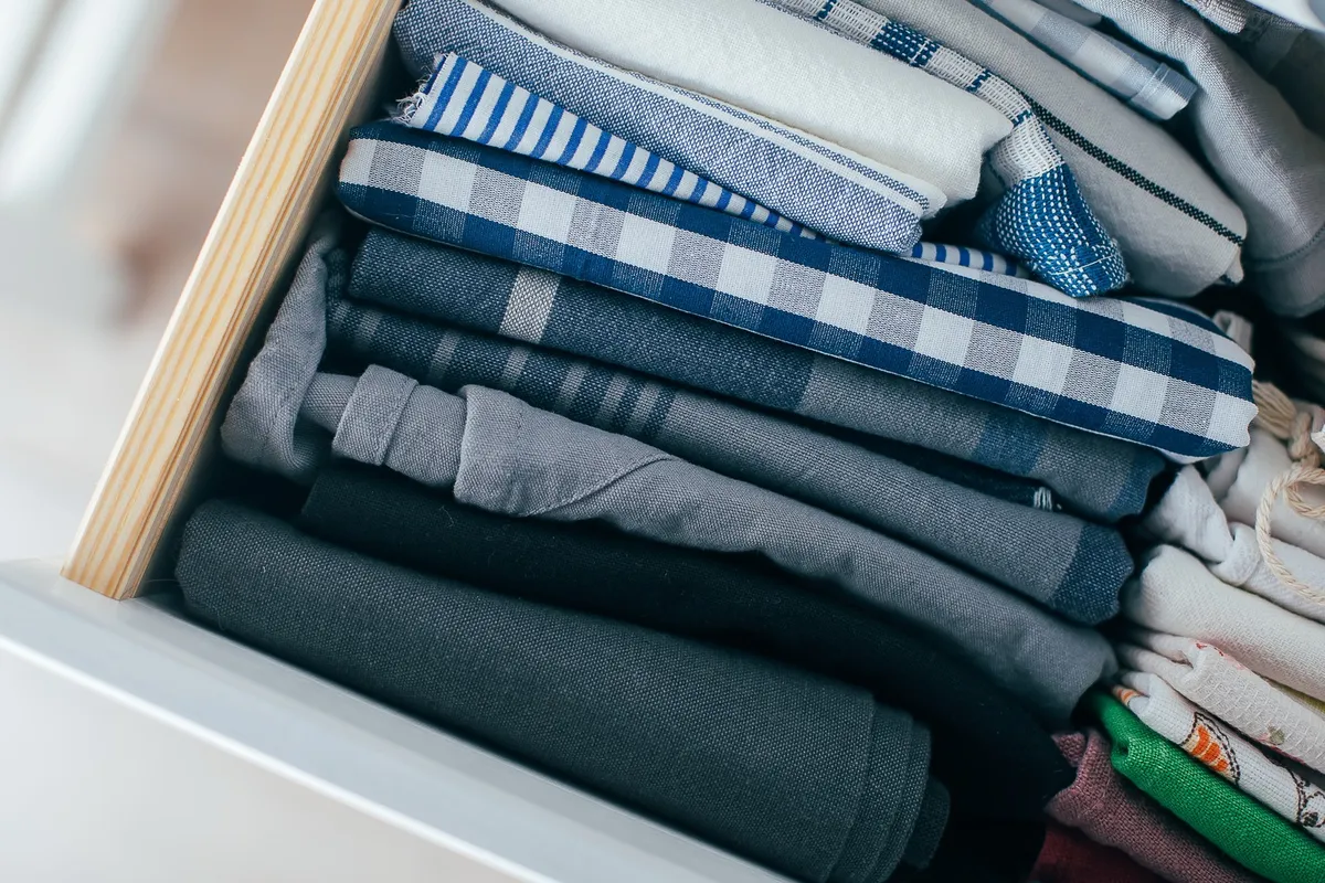 neatly folded long-sleeve shirts standing upright in dresser drawer
