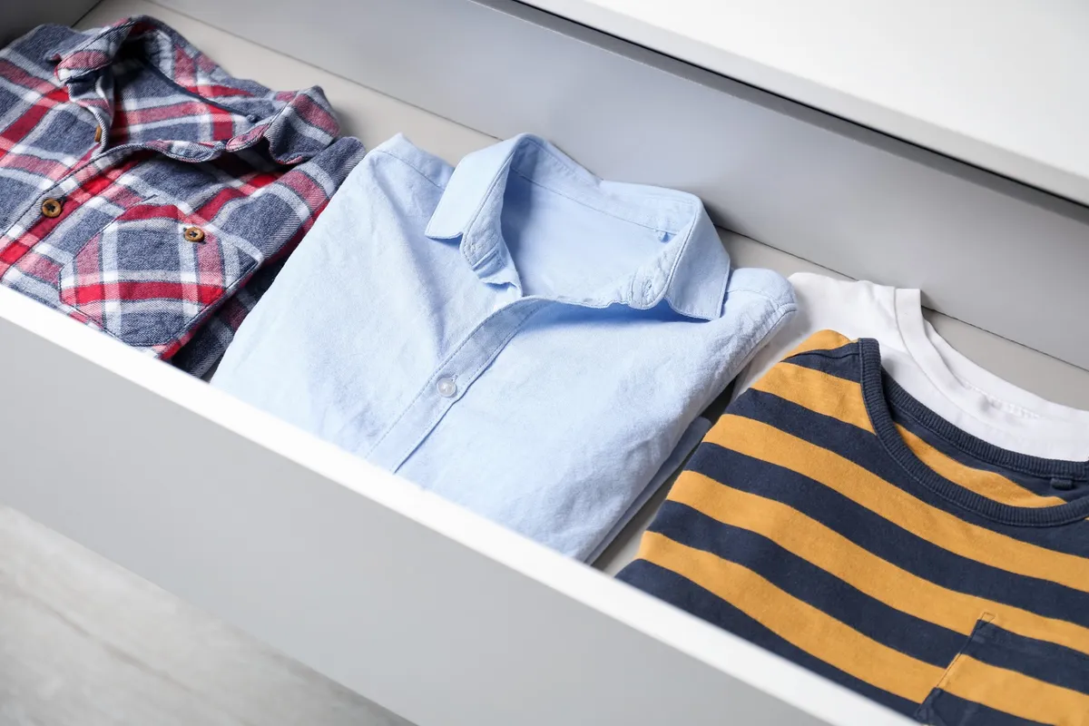 messy open dresser drawer with shirts stacked and tumbling