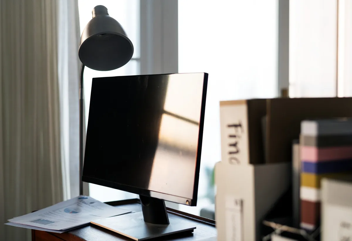 small corner desk with lamp and notebook beside window