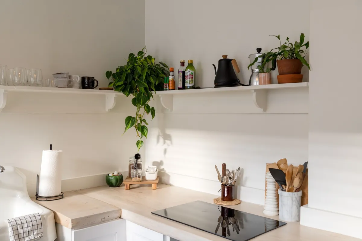 small wood rolling kitchen cart against white wall with shelves