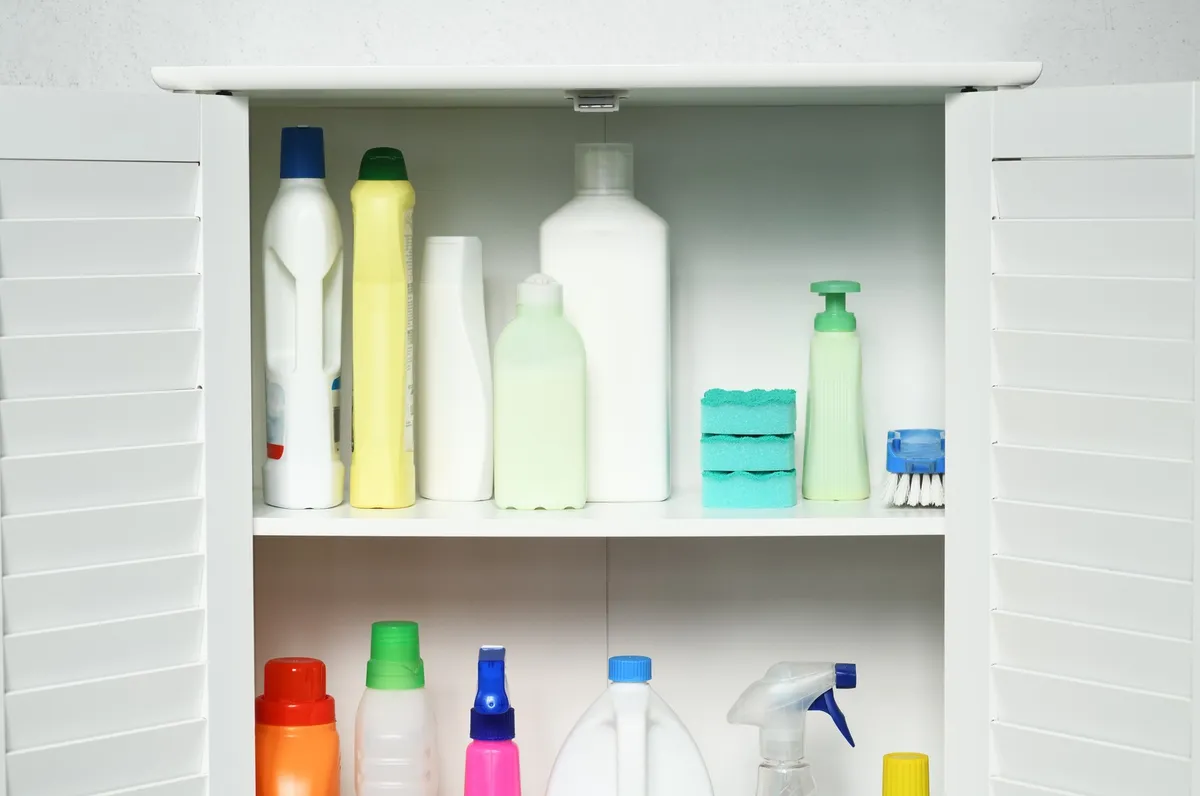 sliding two-tier organizer under kitchen sink with spray bottles