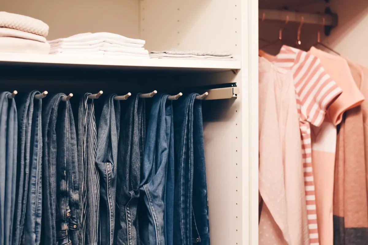 slim white chest of drawers with open drawer showing folded clothes