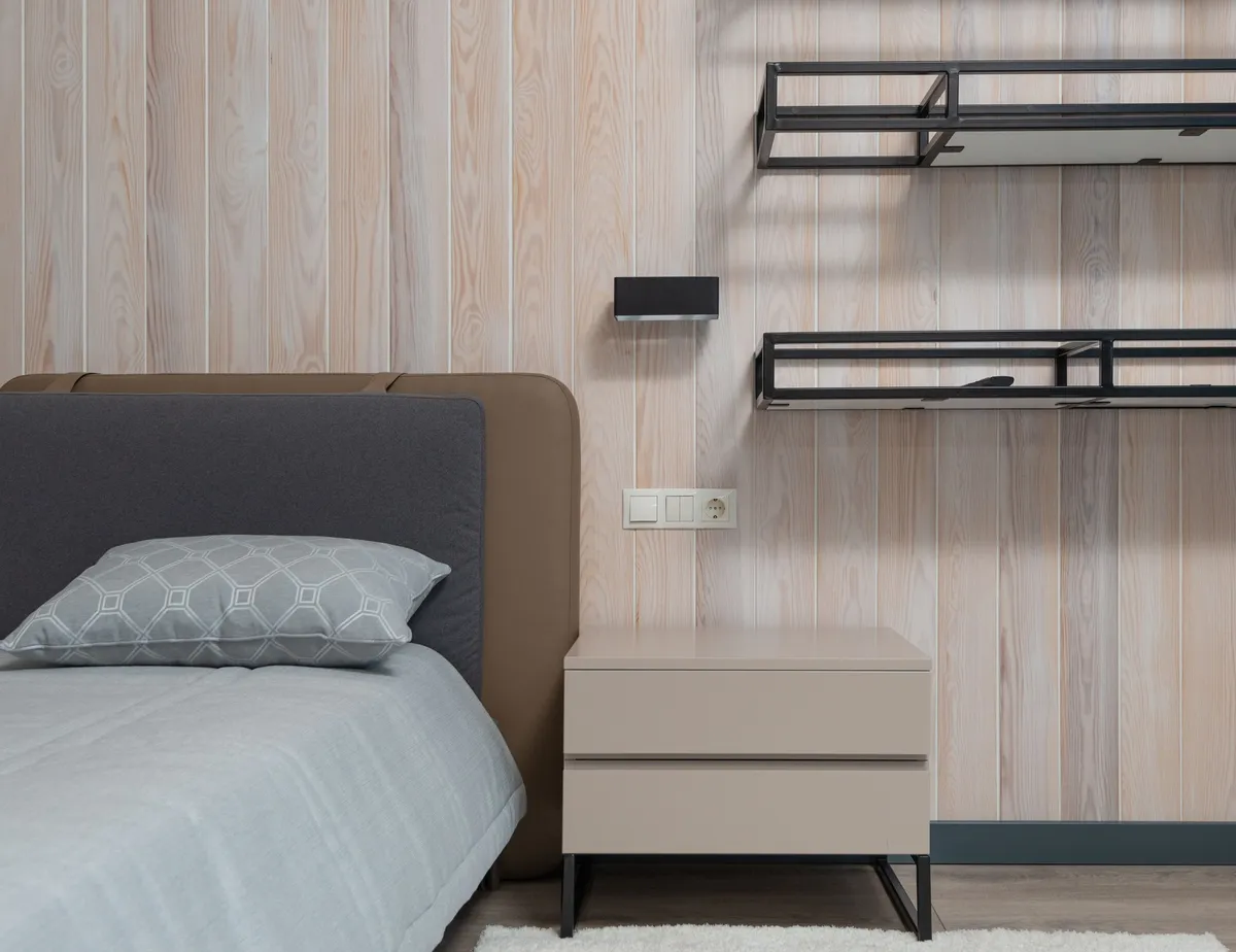 small floating wood shelf beside bed with lamp and book