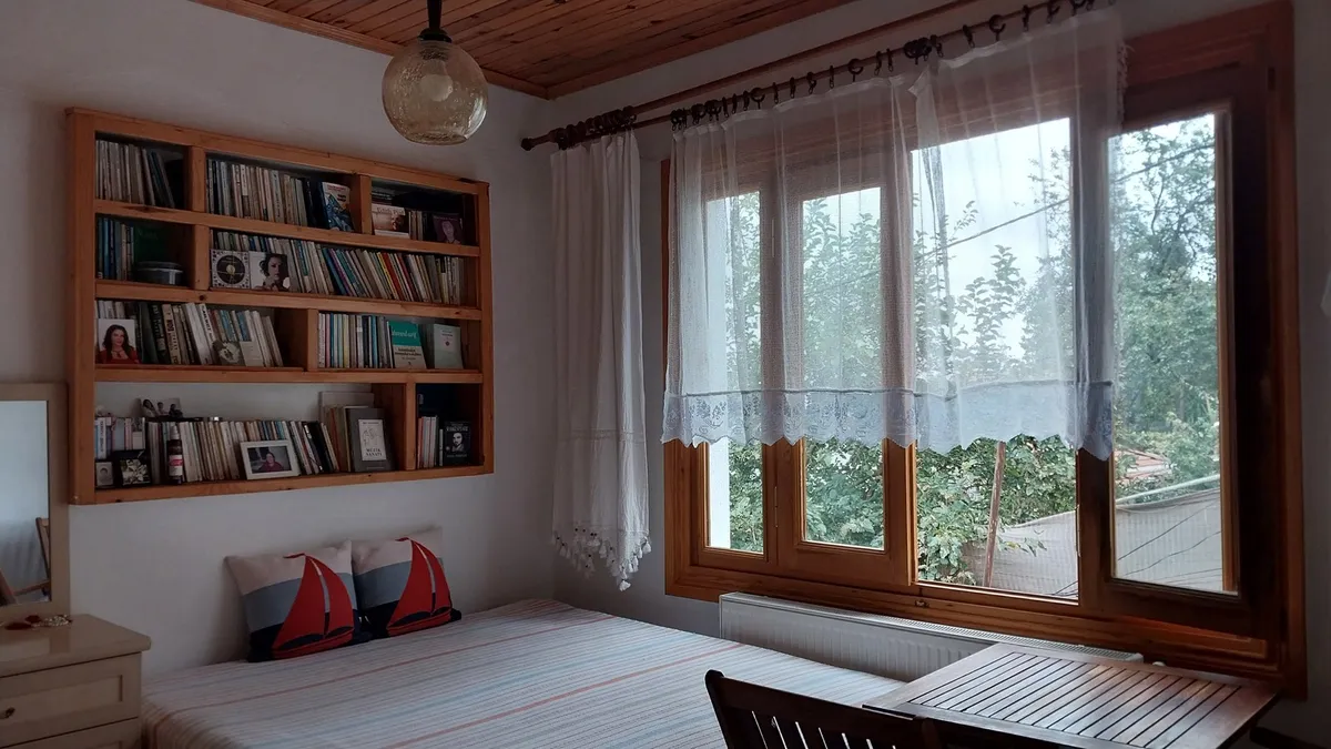 floor-to-ceiling wall shelves in small bedroom with baskets and books