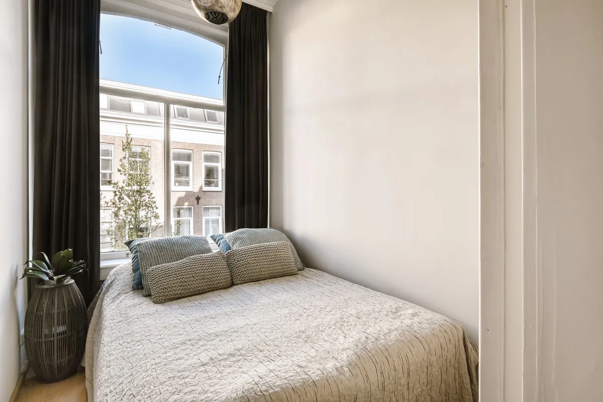 floor-to-ceiling wall shelves in small bedroom with baskets and books