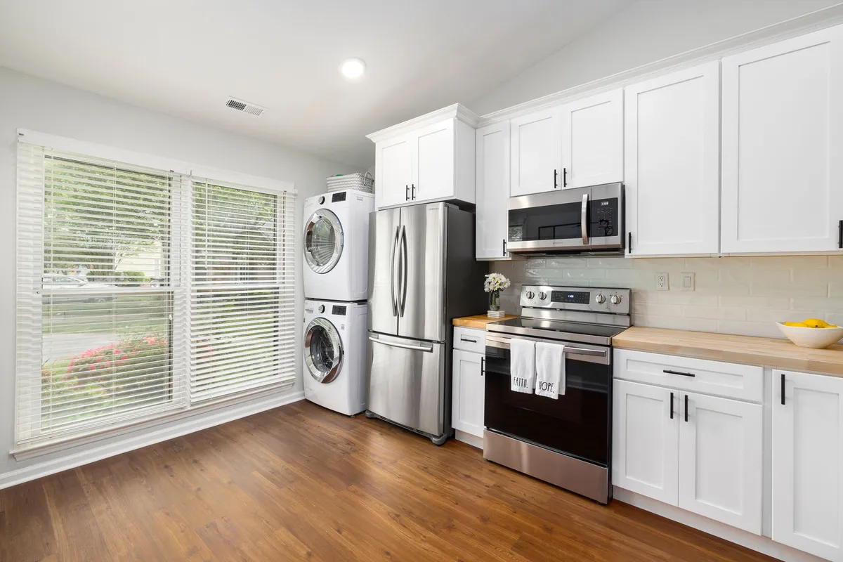 stacked front loading washer dryer in white laundry closet